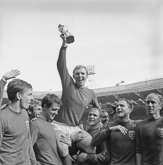 England captain Bobby Moore (1941 - 1993) holds up the Jules Rimet trophy as he is carried on the shoulders of his team-mates after their 4-2 victory over West Germany in the World Cup Final at Wembley Stadium in London, 30th July 1966. Holding him up are (left to right at the front) Martin Peters, Geoff Hurst, Ray Wilson, George Cohen and Bobby Charlton. (Photo by Evening Standard/Hulton Archive/Getty Images)